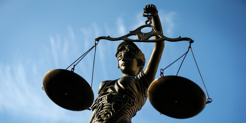Eine Statue der Justitia hält eine Waage in ihrer Hand.