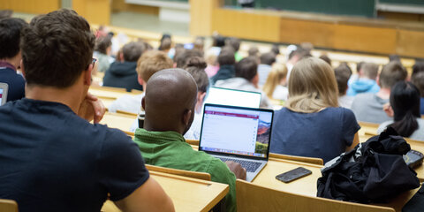 Studierende sitzen mit Laptops in einer Vorlesung.