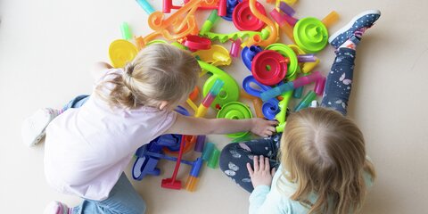 Zwei Kinder spielen in einem Kindergarten auf dem Fußboden.