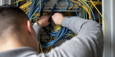 Ein Auszubildender Fachinformatiker Systemintegration bei der IHK Region Stuttgart im 2. Ausbildungsjahr, steckt an einem Server ein Netzwerkkabel ein.