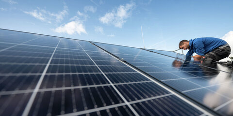 Mitarbeiter montieren Photovoltaikmodule auf dem Dach eines Wohnhauses.