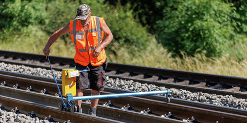Ein Arbeiter überprüft auf einer Bahnstrecke die Gleislage der neu gelegten Schiene.
