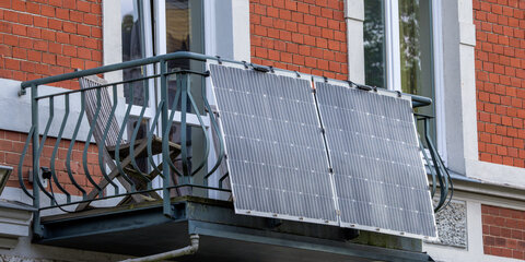 Solarmodule für ein sogenanntes Balkonkraftwerk hängen an einem Balkon in einer Altstadt.
