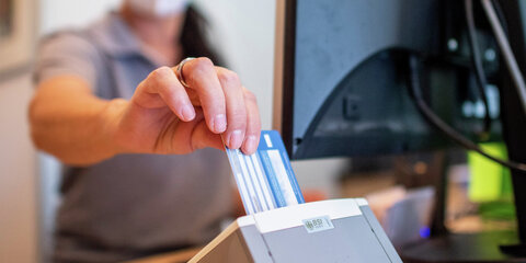 Eine Person schiebt eine Versichertenkarte einer Krankenkasse in ein Lesegerät. Elektronische Rezepte und digitale Patientenakten sollen nach jahrelangen Verzögerungen auf breiter Front zum Einsatz kommen.