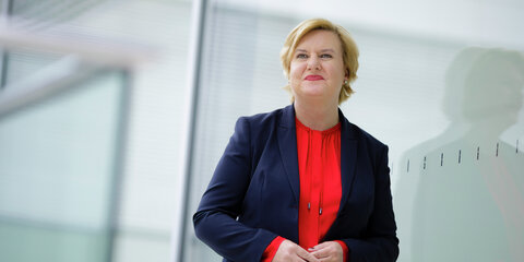 Eva Högl lehnt an einem Fenster und schaut lächelnd in die Ferne.
