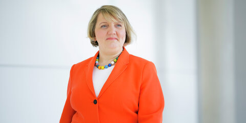 Katja Mast geht über einen Flur und schaut seitlich nach rechts an der Kamera vorbei