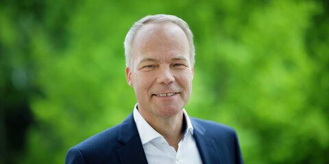 Matthias Miersch steht auf einem Balkon und lächelt in die Kamera.