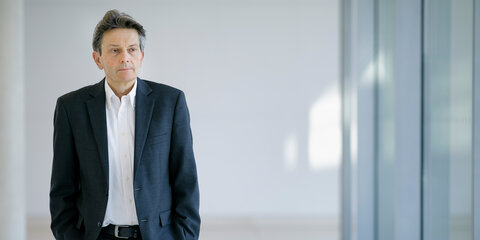 Rolf Mützenich läuft nachdenklich einen Flur entlang.