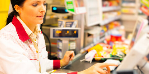 Eine Verkäuferin sitzt an einer Registrierkasse im Supermarkt
