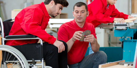 Behinderte Arbeiter im Rollstuhl in einer Tischlerwerkstatt