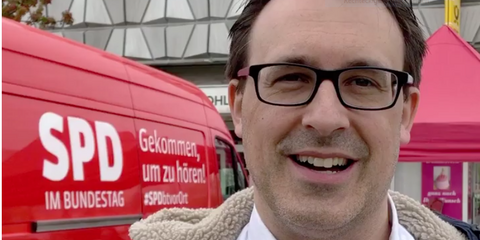 Sören Bartol spricht in die Kamera. Im Hintergrund steht der Dialogbus