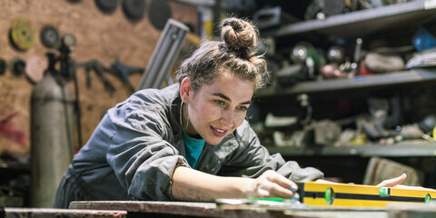 Eine junge Frau arbeitet handwerklich in einer Werkstatt.