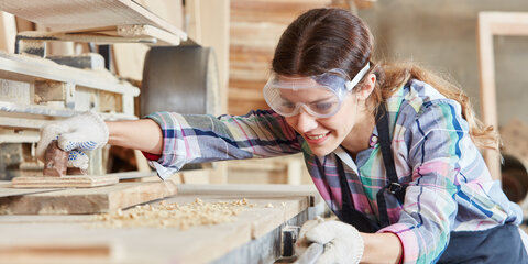 Eine Schreinerin beim Schleifen von Holz