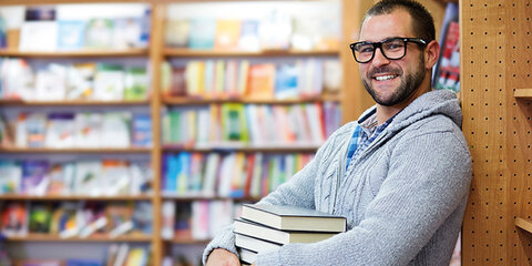 Mann steht in einer Bibliothek mit Büchern