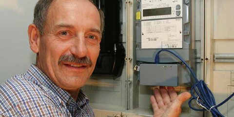 Ein Mann zeigt einen intelligenten Stromzähler, der auch misst, wann der Strom verbraucht wurde.