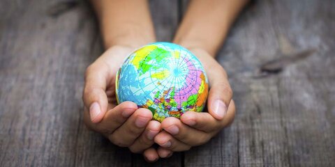 Zwei Hände halten einen kleinen Globus
