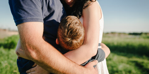 Mama, Papa und Junge laufen im Gras.