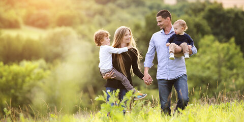 Eine junge Familie, die zusammen Zeit draußen in der grünen Natur verbringt.
