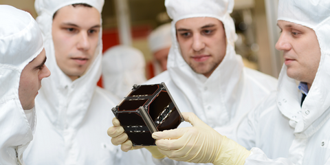 Doktorand Stephan Busch (r) und sein Team betrachten am 19.02.2013 im Testlabor der Uni Würzburg den Kleinsatelliten "Uwe 3". In wenigen Monaten wird der kleine Würfel aus Würzburg mit einer russischen Rakete ins All geschossen. Dort soll der Kleinsatellit monatelang um die Erde kreisen.