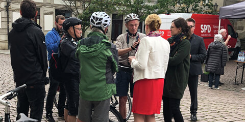 Franziska Giffey steht auf einem Platz und ist im Gespräch mit einer Gruppe Radfahrern.