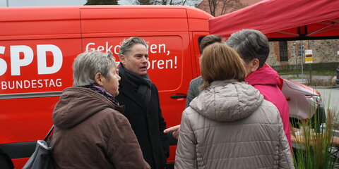 Stefan Zierke steht vor dem roten Tourbus und unterhält sich mit Bürgern