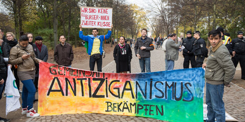 "Gemeinsam Antiziganismus bekämpfen" steht vor dem Mahnmal für Sinti und Roma in Berlin bei einer Kundgebung auf einem Banner.