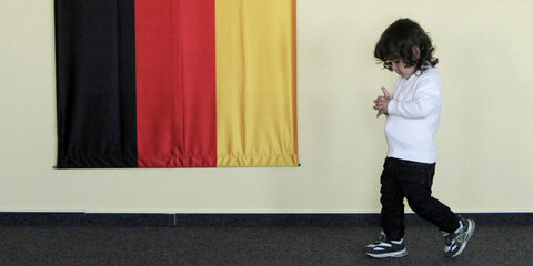 Kleines ausländisches Mädchen in einem Asylbewerber-Erstaufnahmestelle neben einer Deutschlandflagge