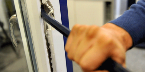 Szene eines simulierten Einbruchs, Hand mit Brechstange an einem Fenster