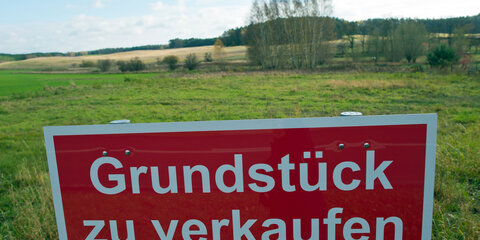 Ein Schild mit der Aufschrift «Grundstück zu verkaufen» steht an einer Straße.