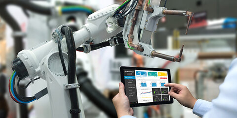 Hand eines Ingenieurs bedient mit seinem Tablet eine Automatisierungsroboterarmmaschine