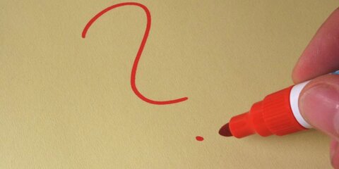 Hand schreibt ein rotes Fragezeichen auf ein Blatt Papier