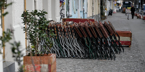Gastronomie-Stühle stehen hochgeklappt an einem Haus in der sonst so belebten Simon-Dach-Straße in Berlin-Friedrichshain. Aufgrund der Corona-Pandemie sind Cafés und Restaurants geschlossen.