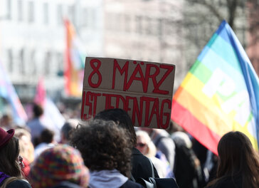 Eine Teilnehmerin hält ein Schild mit der Aufschrift „8. März ist jeden Tag“ auf einer Demonstration zum Internationalen Frauentag.